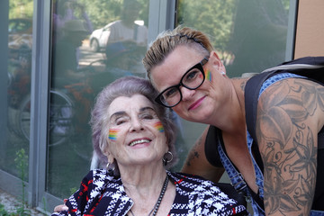 Eine Teilnehmerin im Rollstuhl blickt gemeinsam mit einer anderen Teilnehmerin in die Kamera beim Besuch des Christopher Street Days in Berlin 2026 vom Immanuel Seniorenzentrum Schöneberg.