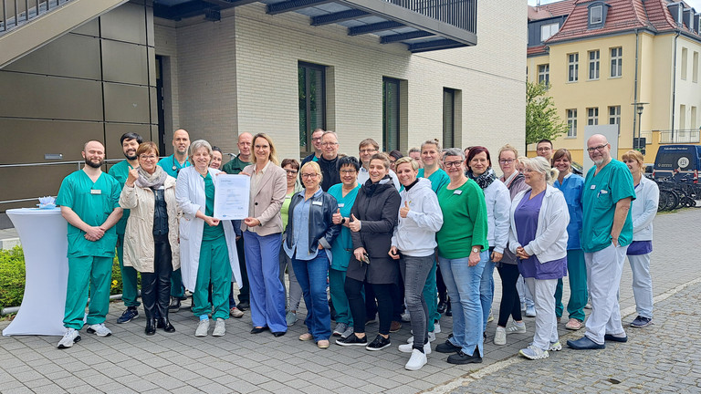 Mitarbeitende des Immanuel Klinikums Bernau vor dem Klinikgebäude mit dem Zertifikat Qualitätszertifikat DIN EN ISO 9001:2015 Mitarbeitende des Immanuel Klinikums Bernau vor dem Klinikgebäude mit dem Zertifikat Qualitätszertifikat DIN EN ISO 9001:2015