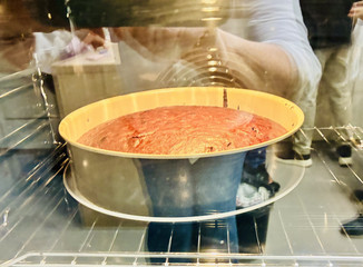 Blick durch die Ofenscheibe auf einen frisch gebackenen Schokoladenkuchen in einer runden Form