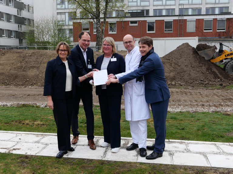 Hamburgs Sozialsenatorin Melanie Schlotzhauer, Amalie-Geschäftsführer Andreas Schneider, Pflegedirektorin Maike Sellentin, der Ärztliche Direktor Prof. Dr. Ernst von Dobschütz und der Konzerngeschäftsführer der Immanuel Albertinen Diakonie Dr. Thorsten Minuth (von links) halten symbolisch den Fördermittelbescheid über 53 Millionen Euro für den Neubau am Evangelischen Amalie Sieveking Krankenhaus in Hamburg-Volksdorf in die Kamera.