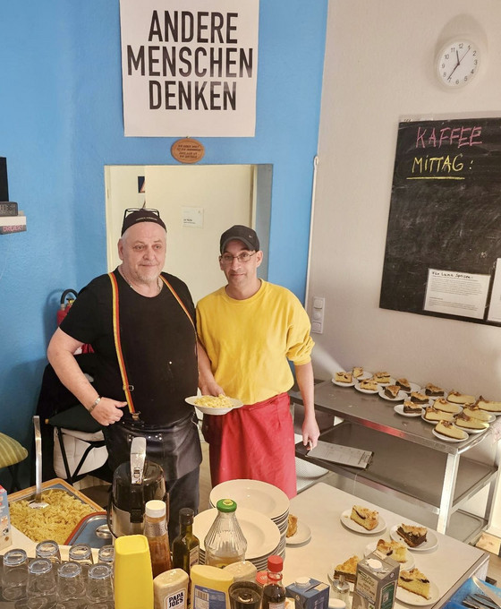 Zwei Männer halten einen Teller bei der Essensausgabe in der Tagesstätte des Sozialprojektes Prenzlauer Berg