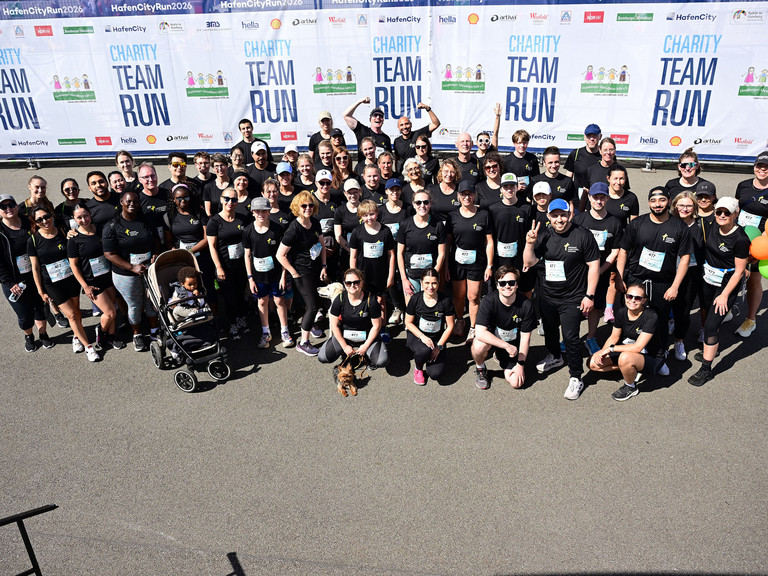 Gruppenfoto der Mitarbeitenden der Immanuel Albertinen Diakonie beim HafenCityRun 2026 in Hamburg. Das Charity-Team posiert vor dem Veranstaltungsbanner nach dem Firmenlauf für den guten Zweck in der HafenCity.
