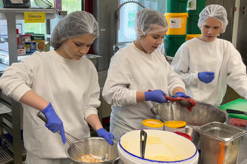 Drei Schülerinnen bereiten beim Girls’ Day unter Anleitung in der Zentralküche der Albertinen Services gemeinsam eine Mahlzeit zu.