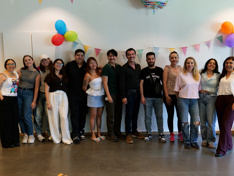 Eine Gruppe internationaler Pflegefachkräfte steht für ein Gruppenfoto zusammen in einem mit Luftballons bunt geschmückten Veranstaltungsraum bei der Anerkennungsfeier für internationale Pflegefachkräfte im Albertinen Krankenhaus in Hamburg.