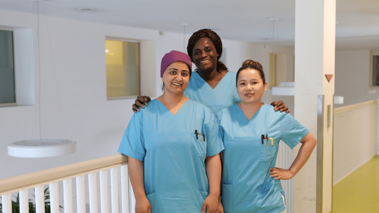 Die Pflegekräfte Yasamin Bahar, Vida Akomah und Dolma Pakhrin blicken im Evangelischen Amalie Sieveking Krankenhaus in Hamburg-Volksdorf in die Kamera