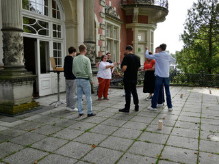 Bei einer Teambuilding-Aktivität auf der Terrasse sollten Holzklötze zu einem Turm aufeinandergestapelt werden, ohne dass dieser umfällt.