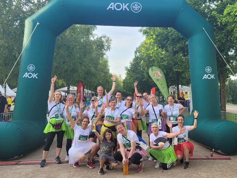 Mitarbeitende aus Pflege, Koordination/Verwaltung, Ehrenamt und Geschäftsführung des Albertinen Hospiz Norderstedt beim AOK-Firmenlauf Norderstedt 2026 blicken gemeinsam im Zieleinlauf ausgelassen und glücklick in die Kamera.
