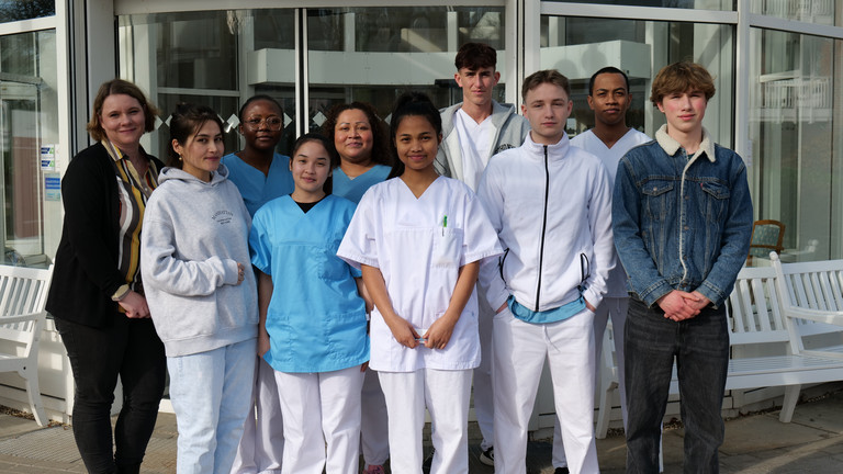Gruppenfoto mit drei neuen Auszubildenden als Pflegefachfrau bzw. zum Pflegefachmann und drei Auszubildenden als Gesundheits- und Pflegeassistenz vor dem Eingang der Residenz am Wiesenkamp mit Petra Furmanski, hauptamtliche Praxisanleiterin und Ansprechpartnerin für die Auszubildenden.