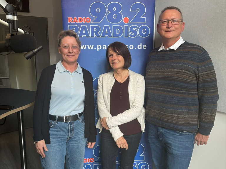 Nicole Oerder, Julia Nogli und Ralf Schäfer vor einem Aufsteller von Radio Paradiso - Immanuel Seniorenzentrum Schöneberg - Lebensort Vielefalt 