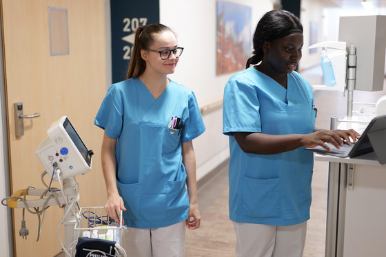 Zwei Pflegerinnen gehen mit Stationswagen und medizinischem Gerät über den Stationsflur der Kardiochirurgie im Albertinen Krankenhaus, Hamburg-Schnelsen