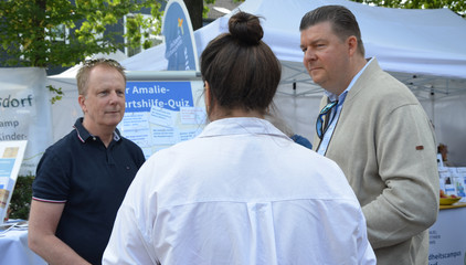 Hamburgs Finanzsenator Andreas Dressel (r.) unterhält sich mit zwei Personen an den Ständen des Gesundheitscampus Volksdorf der Immanuel Albertinen Diakonie beim Stadtteilfest Volksdorf in Hamburg