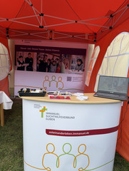 Ein Infostand mit Tisch, Plakat und Informationsmaterial zur Einrichtung und Stellenangeboten beim Fest zum 25-jährigen Jubiläum des Immanuel Suchthilfeverbunds Guben mit besonderen Wohnformen für abhängigkeitskranke Menschen in Thüringen Ein Infostand mit Tisch, Plakat und Informationsmaterial zur Einrichtung und Stellenangeboten beim Fest zum 25-jährigen Jubiläum des Immanuel Suchthilfeverbunds Guben mit besonderen Wohnformen für abhängigkeitskranke Menschen in Thüringen