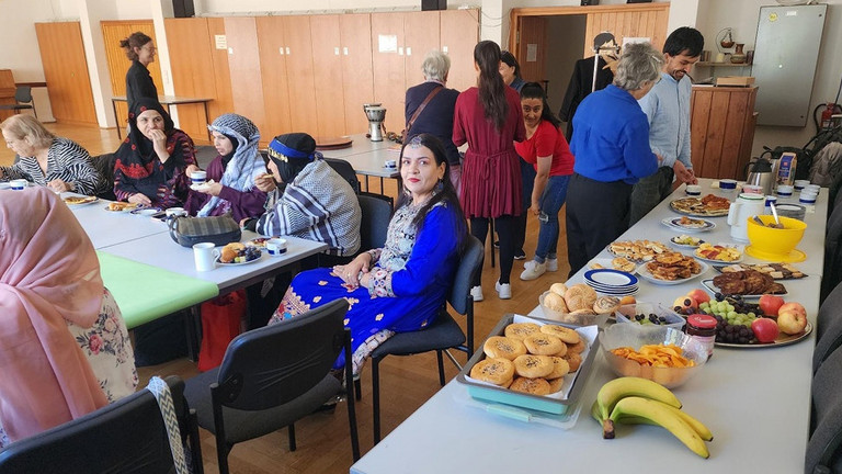 Buffet uns Frauen, die an Tischen sitzen und essen und trinken Buffet uns Frauen, die an Tischen sitzen und essen und trinken