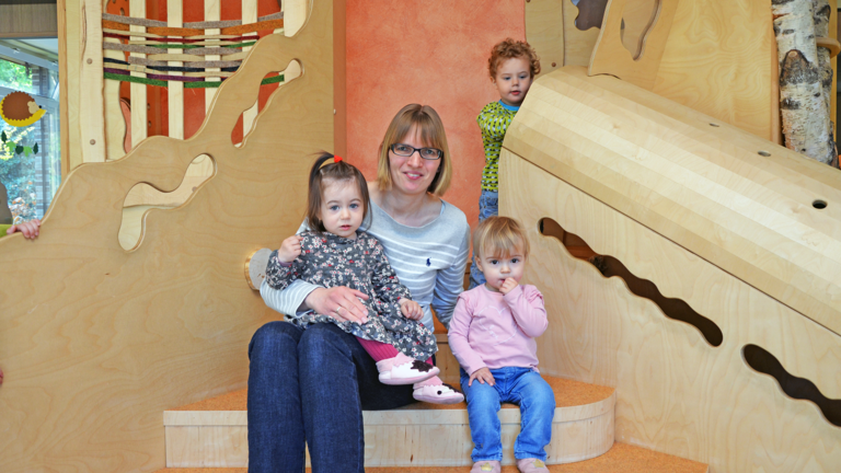 Eine Erzieherin sitzt mit Kindern um sich auf einer Treppe, arbeiten in der Albertinen Kindertagesstätte Volksdorf, Karriere in der Immanuel Albertinen Diakonie, Hamburg-Volksdorf