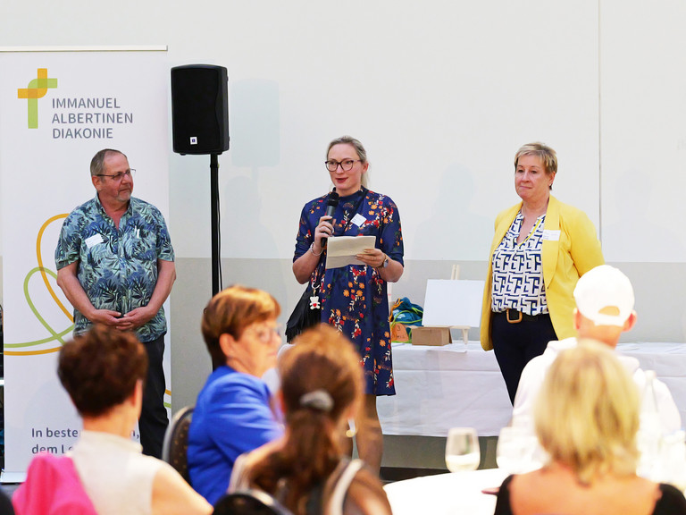 v.l.n.r. stehen die Sprecherinnen und Sprecher der Pflegefachkonferenz Thomas Fricke, Joanna Strozyk und Martina Kringe bei der Moderation des Pflegefachtags auf der Bühne