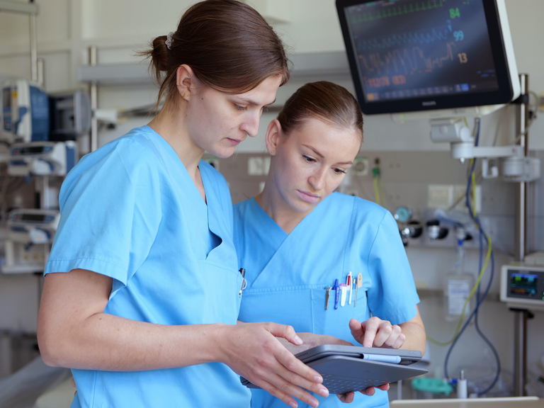 Zwei Pflegekräfte blicken auf Tablet und tauschen sich aus im Albertinen Krankenhaus in Hamburg-Schnelsen