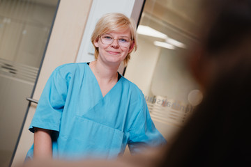 Eine Pflegerin im blauen Kasack bei der pflegerischen Arbeit im Patientenzimmer im Albertinen Krankenhaus Hamburg Schnelsen
