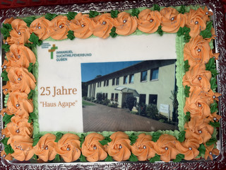 Ein großer quadratischer Kuchen mit essbaren Rosen und Foto und Schrift aus Zuckerguss zum 25-jährigen Jubiläum des Immanuel Suchthilfeverbunds Guben mit besonderen Wohnformen für abhängigkeitskranke Menschen in Thüringen Ein großer quadratischer Kuchen mit essbaren Rosen und Foto und Schrift aus Zuckerguss zum 25-jährigen Jubiläum des Immanuel Suchthilfeverbunds Guben mit besonderen Wohnformen für abhängigkeitskranke Menschen in Thüringen