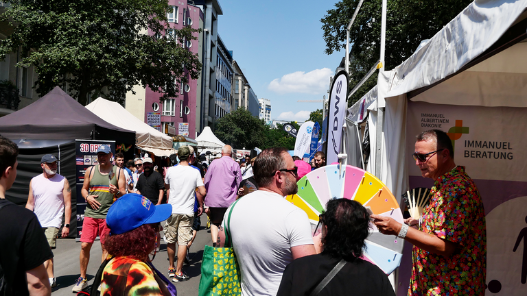 Stand mit Glücksrad und vielen Menschen Stand mit Glücksrad und vielen Menschen