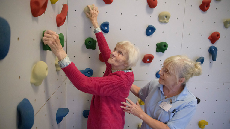 Bewohnerin einer Pflegeeinrichtung trainiert mit therapeutischer Unterstützung ihre Mobilität im Rahmen des Pilotprojekts SGB Reha im Albertinen Haus Hamburg.