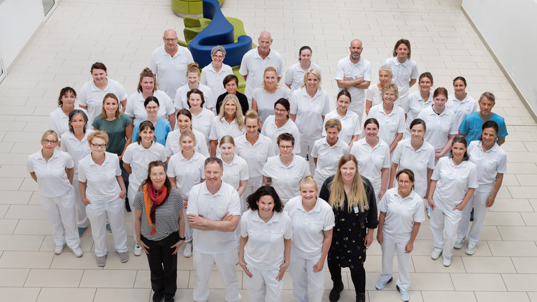 Das Team des Interdisziplinären Therapiezentrums des Albertinen Krankenhauses in Hamburg Schnelsen steht im Innenhof und strahlt nach oben in die Kamera Das Team des Interdisziplinären Therapiezentrums des Albertinen Krankenhauses in Hamburg Schnelsen steht im Innenhof und strahlt nach oben in die Kamera
