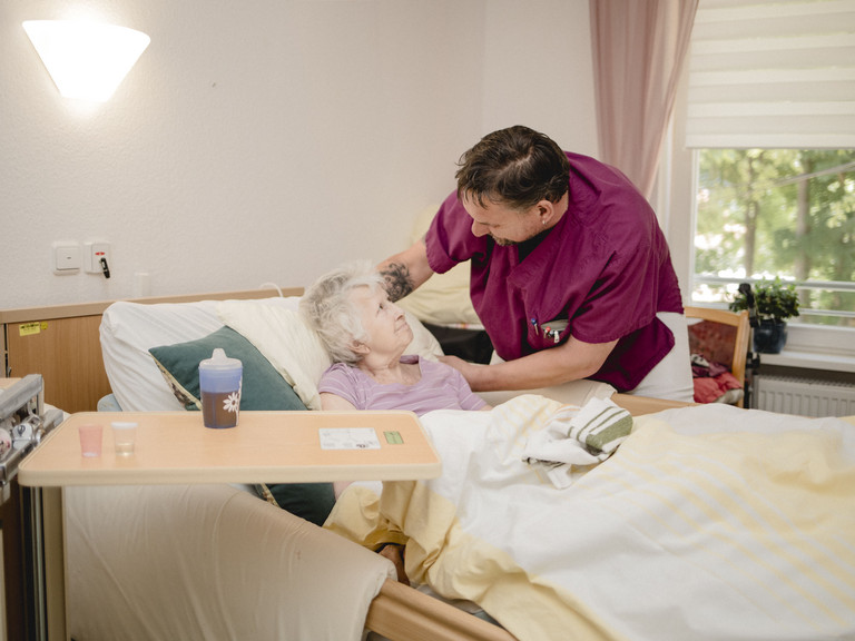 Ein Pfleger unterhält sich mit einer Seniorin im Pflegezimmer im Seniorenzentrum Kläre Weist in Petershagen