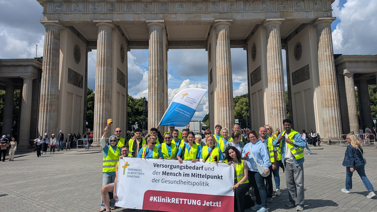 Mitarbeitende mit Banner vor Brandenburger Tor Mitarbeitende mit Banner vor Brandenburger Tor