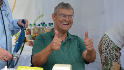 Ein Mann streckt beide Daumen hoch und blickt in die Kamera bei den Ständen des Gesundheitscampus Volksdorf der Immanuel Albertinen Diakonie beim Stadtteilfest Volksdorf in Hamburg