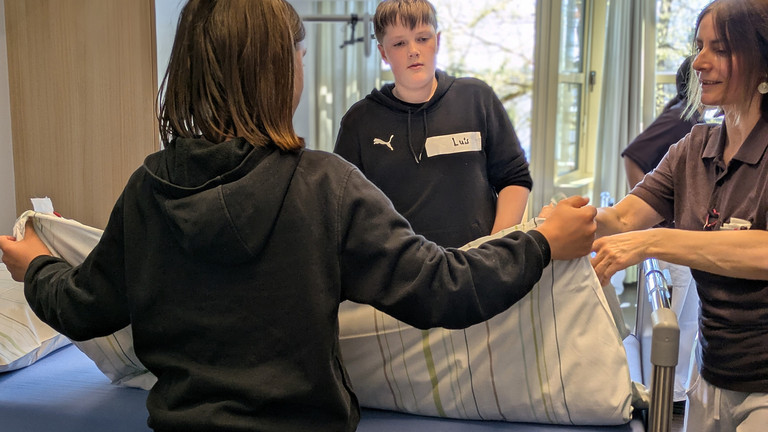 Junge hebt fertig bezogene Bettdecke an - Boys Day bei Immanuel Dienstleistungen