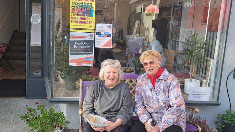 Zwei Damen sitzen auf Bank vor dem Stadtteilzentrum Borsigwalde