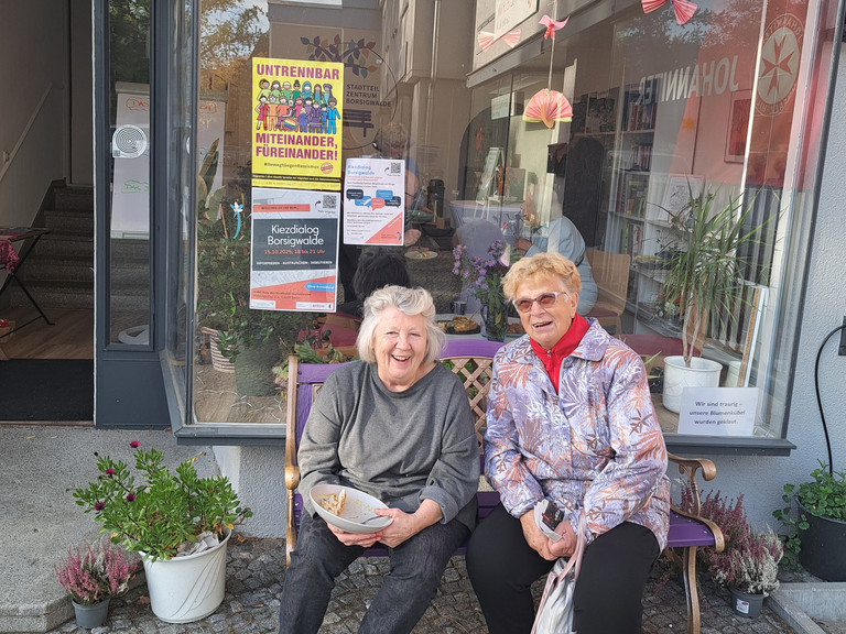 Zwei Damen sitzen auf Bank vor dem Stadtteilzentrum Borsigwalde