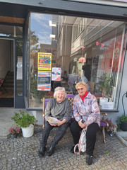 Zwei Nachbarinnen haben es sich auf der Bank vor dem Stadtteilzentrum gemütlich gemacht