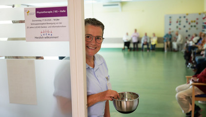 Eine Mitarbeiterin in Funktionskleidung steht lächelnd in der Eingangstür zum großen Saal bei der Jubiläumsveranstaltung mit Symposium und einer Dankesveranstaltung zum 25-jährige Bestehen der LUCAS Langzeit-Kohortenstudie im Hamburger Albertinen Haus und Kirche am Albertinen Krankenhaus. Eine Mitarbeiterin in Funktionskleidung steht lächelnd in der Eingangstür zum großen Saal bei der Jubiläumsveranstaltung mit Symposium und einer Dankesveranstaltung zum 25-jährige Bestehen der LUCAS Langzeit-Kohortenstudie im Hamburger Albertinen Haus und Kirche am Albertinen Krankenhaus.