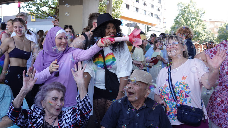 Eine Gruppe fröhlicher Menschen unterschiedlichen Alters mit einer Seifenblasenmaschine beim Besuch des Christopher Street Days in Berlin 2026 vom Immanuel Seniorenzentrum Schöneberg.