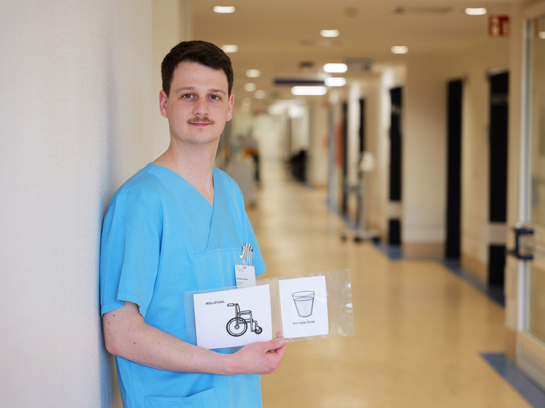 Kilian Müller, Stationsleitung der neurologischen Frührehabilitation im Albertinen Krankenhaus, zeigt Piktogramme zur Unterstützung der Kommunikation mit Patientinnen und Patienten nach Schlaganfall