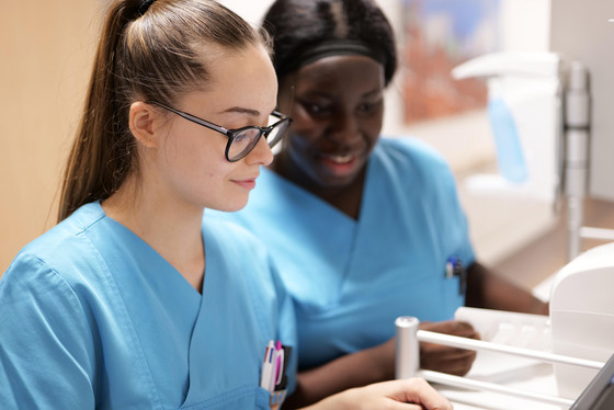 Zwei Pflegekräfte blicken auf einen Computer und Unterlagen in der Pflegestation Orthopaedie und Urologie im Albertinen Krankenhaus, Hamburg-Schnelsen 