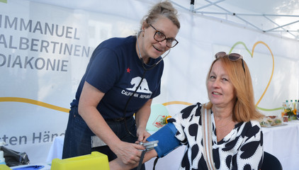 Eine Mitarbeiterin misst den Blutdruck einer Besucherin bei den Ständen des Gesundheitscampus Volksdorf der Immanuel Albertinen Diakonie beim Stadtteilfest Volksdorf in Hamburg