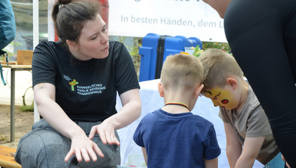 Zwei Kinder mit einer Mitarbeiterin bei einer Übung an den Ständen des Gesundheitscampus Volksdorf der Immanuel Albertinen Diakonie beim Stadtteilfest Volksdorf in Hamburg