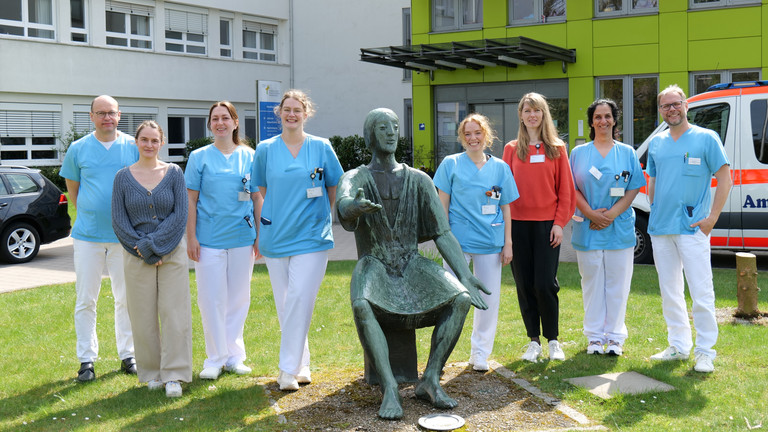 Mehrere neue Ärztinnen stehen mit Prof. von Dobschütz, dem Ärztlichen Direktor, sowie Prof. Matthias Grünewald, Chefarzt Anästhesie und Intensivmedizin, für ein Gruppenfoto vor dem Amalie Sieveking Krankenhaus mit einer Bronzefigur von Amalie Wilhelmine Sieveking beim Einführungstag für neue Ärztinnen und Ärzte.