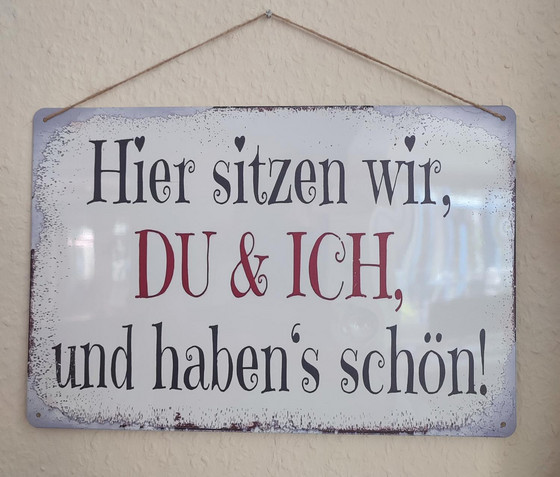 Ein Schild mit der Aufschrift "Hier sitzen wir, Du und Ich, und haben´s schön" hängt im Büro in der Verwaltung der Senioreneinrichtung Immanuel Haus Ecktannen in Waren (Müritz)