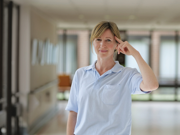 Eine Pflegefachkraft steht in einem Stationsflur, blickt in die Kamera und berührt mit dem Finger ihre Stirn im Albertinen Zentrum für Altersmedizin in Hamburg-Schnelsen Eine Pflegefachkraft steht in einem Stationsflur, blickt in die Kamera und berührt mit dem Finger ihre Stirn im Albertinen Zentrum für Altersmedizin in Hamburg-Schnelsen