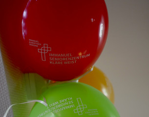Luftballons in rot, grün und organge mit dem Kreuzbandlogo und dem Namen der Einrichtung bei der Wiedereröffnung der Tagespflegestätte für ältere Menschen im Immanuel Seniorenzentrum Kläre Weist in Petershagen Luftballons in rot, grün und organge mit dem Kreuzbandlogo und dem Namen der Einrichtung bei der Wiedereröffnung der Tagespflegestätte für ältere Menschen im Immanuel Seniorenzentrum Kläre Weist in Petershagen