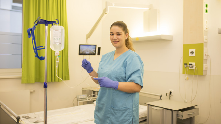 Eine Pflegefachfrau steht am Tropf vor einem Patientenbett, Ausbildung in der Pflege, arbeiten in der Residenz am Wiesenkamp, Karriere in der Immanuel Albertinen Diakonie, Hamburg-Volksdorf Eine Pflegefachfrau steht am Tropf vor einem Patientenbett, Ausbildung in der Pflege, arbeiten in der Residenz am Wiesenkamp, Karriere in der Immanuel Albertinen Diakonie, Hamburg-Volksdorf