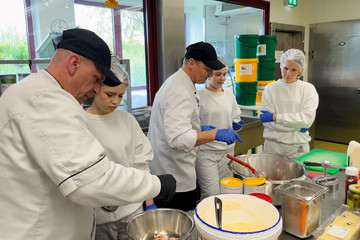 Mitarbeiter der Zentralküche zeigen Schülerinnen beim Girls’ Day praktische Arbeitsschritte bei der Zubereitung von Speisen.
