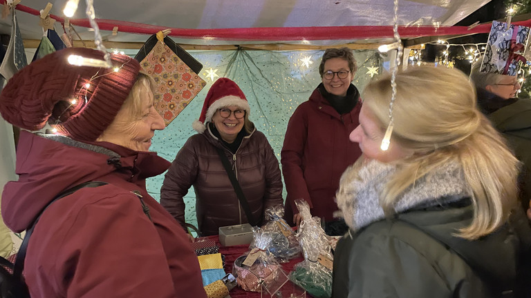 Hospizmitarbeitende und -gäste an einem Adventsmarktstand, Veranstaltung im Hospiz, Weihnachtsmarkt für Mitarbeitende und Gäste im Hospiz, Diakonie Hospiz Wannsee, Berlin-Wannsee