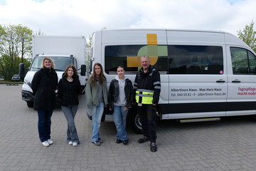 Drei Schülerinnen stehen beim Girls’ Day mit Mitarbeitenden vor einem Fahrzeug der Albertinen Services Hamburg.