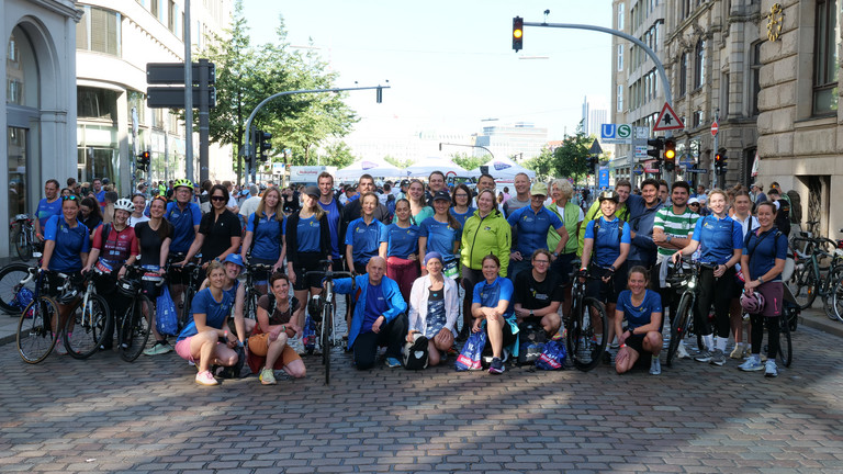 Eine Gruppe von Mitarbeiterinnen und Mitarbeitern der Immanuel Albertinen Diakonie die beim Hamburger Triathlon gestartet sind, sie tragen bunte Trikots
