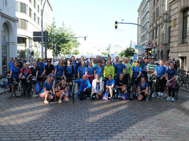 Eine Gruppe von Mitarbeiterinnen und Mitarbeitern der Immanuel Albertinen Diakonie die beim Hamburger Triathlon gestartet sind, sie tragen bunte Trikots