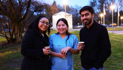 Drei Mitarbeitende mit Bechern in der Hand blicken vor dem Festzelt fröhlich in die Kamera bei der Weihnachtsfeier 2025 von Amalie Sieveking Krankenhaus, Residenz am Wiesenkamp, Feierabendhaus Volksdorf und Albertinen Kindertagesstätte Volksdorf auf dem Gesundheitscampus Volksdorf in Hamburg