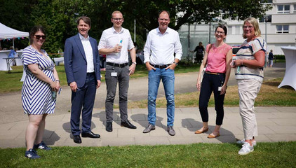 Dr. Thorsten Minuth, Konzerngeschäftsführer Immanuel Albertinen Diakonie, Krankenhaus-Geschäftsführer Andreas Schneider und Pflegedirektorin Maike Sellentin stehen mit mehreren Mitarbeitenden zusammen und blicken in die Kamera beim Sommerfest 2026 auf dem Gesundheitscampus Volksdorf des Evangelischen Amalie Sieveking Krankenhauses, der Residenz am Wiesenkamp, des Feierabendhauses Volksdorf und der Albertinen Kindertagesstätte Volksdorf. 